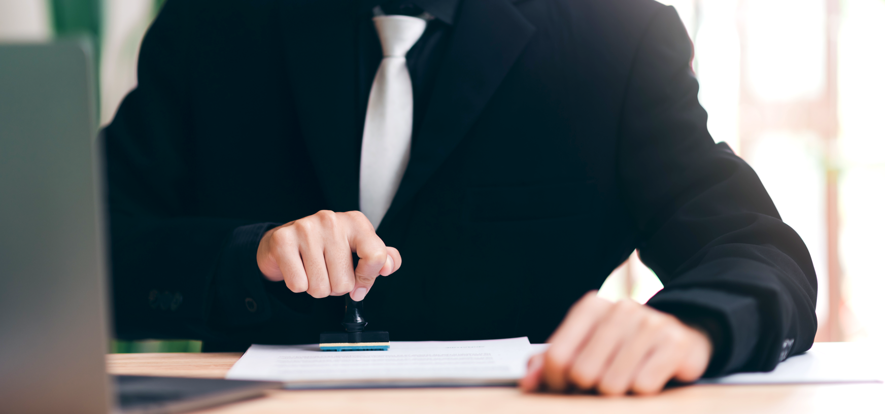 Man signing a document in an office, illustrating the use of time stamps for chronological validation and digital security.